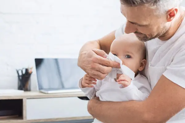 Bébé avec un rhume, entouré de granules homéopathiques
